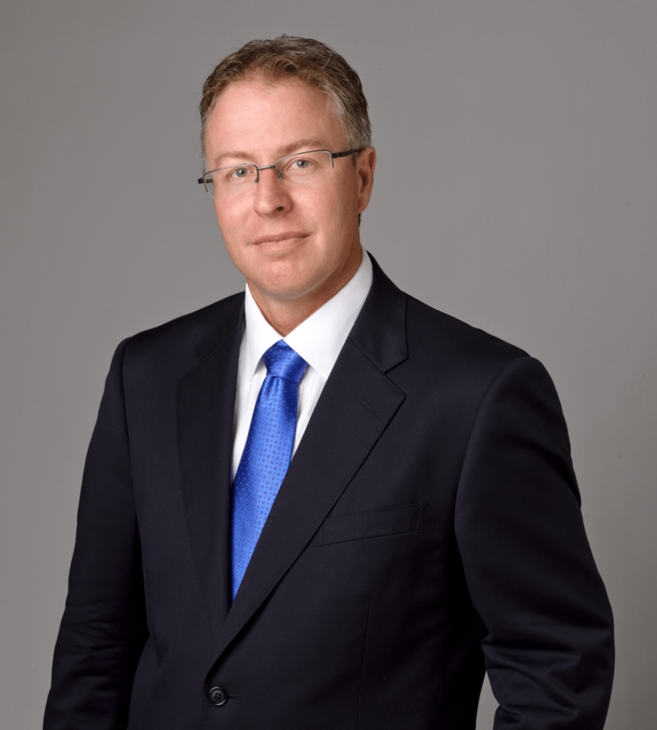 Portrait of Liam Johnson in a dark suit, glasses and blue tie, team member photo in the Layout 3 team section demo